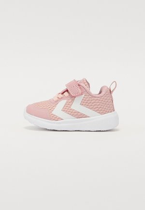 Roze sportschoen gemaakt van ademend meshmateriaal, met witte zigzagaccenten, een klittenbandsluiting en een rubberen zool voor grip.