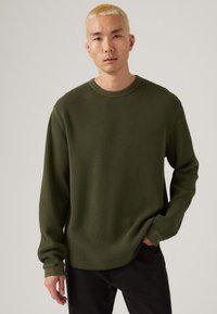 Olijfgroene geribde langemouwen shirt met een ronde hals en verlaagde schouders, met een textuurstof en een licht gebogen zoom.