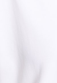 Effen wit katoen met een gladde textuur en subtiele vouwen, gelijkmatig verlicht zonder extra objecten of elementen.