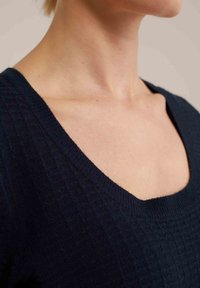 Merihenkinen neulepaita, jossa on leveä V-pääntie ja teksturoitu kuvio, esittelee iholle miellyttävän pehmeää kangasta.