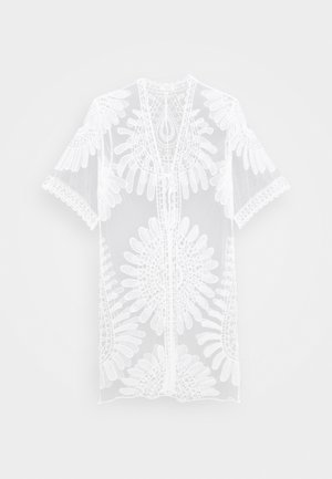 Weiße transparente Spitzen-Tunika mit floralen und geometrischen Stickmustern, kurzen Ärmeln und rundem Ausschnitt.