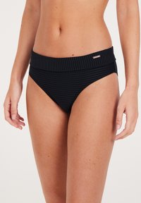 Bikini in nero a coste con un ampio elastico in vita e dettagli sottili. Il tessuto ha una finitura testurizzata, offrendo una vestibilità elegante.