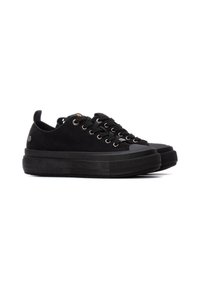 Zapatillas negras de ante con una suela de goma texturizada, que cuentan con ojales plateados, una suela gruesa y una pestaña en el talón para facilitar su puesta.