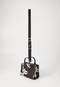 Borsa in tessuto nero con motivo floreale bianco, manici corti e una tracolla nera regolabile, dotata di chiusura superiore a zip e tasche aggiuntive.