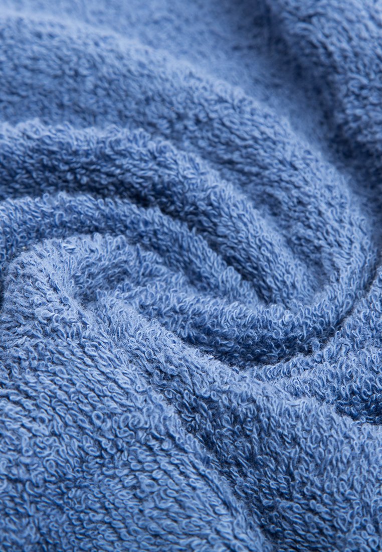Tessuto della asciugamano blu con texture, caratterizzato da una superficie morbida e soffice con anelli visibili, disposti in un motivo a spirale. Materiale spesso e assorbente.