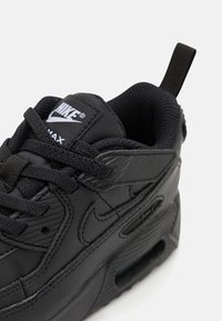Mustad mustad mustad Nike Air Max tossud, millel on tekstuuriga nahk, pehmendatud kaelus, nöörid ja silmatorkav brändimine keele ja külje peal.
