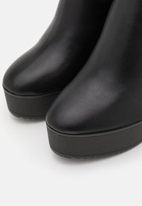 Black platform boots with a smooth leather texture, rounded toe, and a thick black sole. No notable patterns or hardware visible.