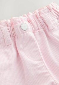 Shorts roses clairs avec de subtils rayures blanches, dotés d'une taille élastique, d'une fermeture à bouton et de deux poches latérales. Texture en coton lisse.