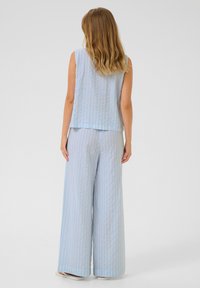 Un haut sans manches bleu clair rayé et un pantalon large en tissu texturé. Une coupe décontractée avec des rayures verticales subtiles et une finition ourlée.