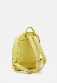 Żółty zamszowy plecak o zaokrąglonym kształcie, z regulowanymi paskami na ramiona, górnym uchwytem oraz minimalistycznymi detalami szwów.