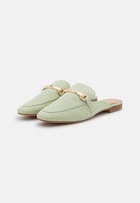 Mules en suédine vert menthe, à enfiler, avec un bout pointu, ornées d'une chaîne décorative dorée sur le devant et d'un petit talon en bois.