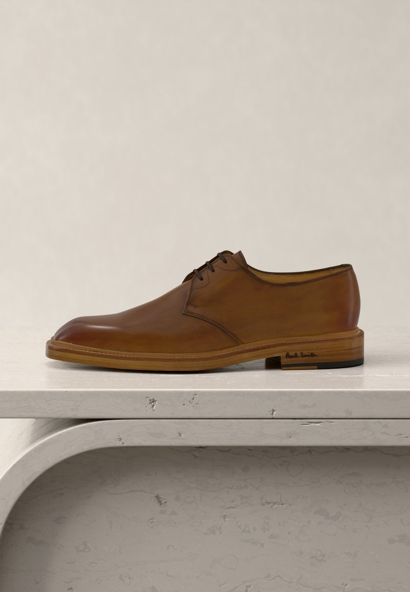 Chaussure habillée pour homme en cuir marron avec lacets noirs, semelle en bois et talon bas, posée sur une surface en pierre beige texturée.