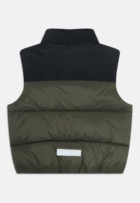Polstret ärmløs vest med mørk overdel og olivengrønn underdel, med en liten rektangulær reflekterende etikett nær bunnen.