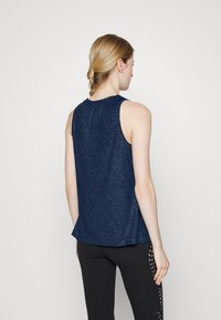 Top sem mangas azul-marinho com um padrão texturizado, decote arredondado e um corte descontraído, combinado com leggings pretas com detalhes vazados.