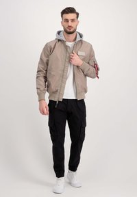 Karamelli pommertagi halli kapuutsiga, soonikkoes varrukad ja küljetasku. Kombineeritud mustade cargo-pükste ja valgete tennisekingadega.