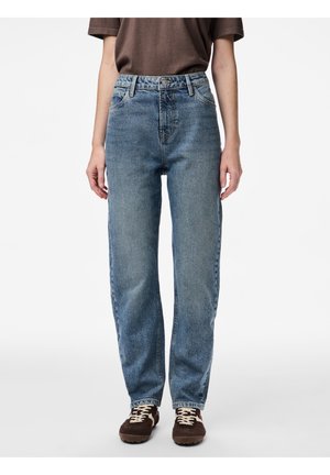 Persoon draagt blauwe high-waist jeans met een losse pasvorm, een bruin kort mouwtopje en bruine sneakers met witte veters op een witte achtergrond.