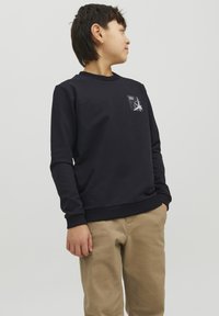 Felpa blu scuro a maniche lunghe, con polsini a coste e scollatura rotonda. Presenta una piccola patch grafica bianca sul petto.