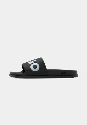 Black slide sandal made from synthetic material featuring a wide strap with a large gray circle design and textured footbed for grip.