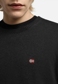 Maglione nero a maglia con collo rotondo, caratterizzato da una piccola bandiera ricamata in rosso, bianco e blu sul petto. Tessuto a trama.