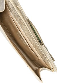 Wnętrze złotej torebki ze skórzanym wykończeniem, ukazujące przegródki, zamek błyskawiczny oraz metalowy akcent z logo na skórzanej zawieszce.