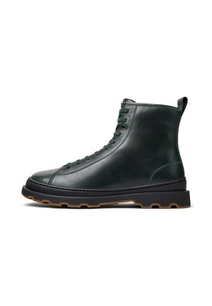 Leather ankle boots in dark green with round toe, lace-up design, and contrasting black outsole. Features a pull tab on the heel.