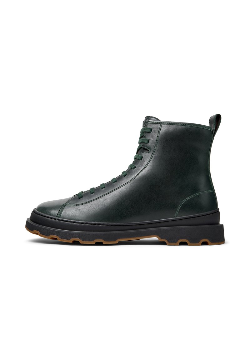 Botas de tobillo de cuero en verde oscuro con puntera redonda, diseño de cordones y suela negra contrastante. Cuenta con una pestaña en el talón.