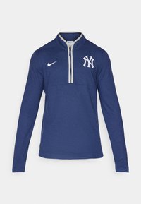 Námořnická modrá mikina s dlouhým rukávem a polo zipem, s bílým logem Nike a bílým emblémem New York Yankees na hrudi.