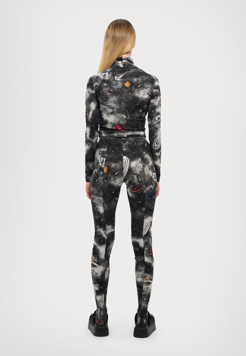 Mono ajustado de manga larga con un estampado de temática espacial que incluye planetas y estrellas sobre un fondo negro. Tejido elástico y diseño elegante.