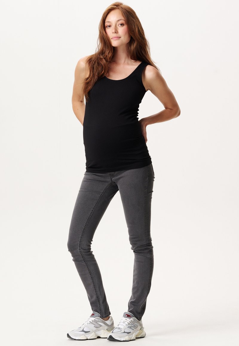 Top de tirantes negro acanalado combinado con jeans ajustados grises y zapatillas deportivas grises, con un diseño sencillo y un estilo cómodo.