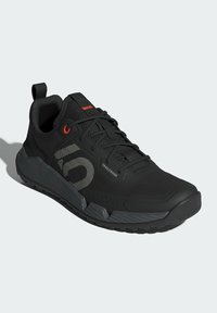 Czarne buty sportowe z teksturowaną cholewką, wzmocnionym czubkiem, szarymi akcentami oraz wytrzymałą gumową podeszwą z wzorzystym bieżnikiem dla lepszej przyczepności.