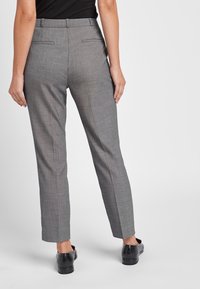 Grijze op maat gemaakte broek met een subtiele ruitpatroon, rechte pasvorm, paspelzakken aan de achterkant en een gladde stofstructuur.