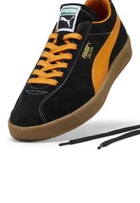 Czarny zamszowy sneaker Puma z pomarańczowymi paskami, pomarańczowymi sznurówkami i gumową podeszwą, z widocznym logo Puma i dodatkową parą czarnych sznurówek.