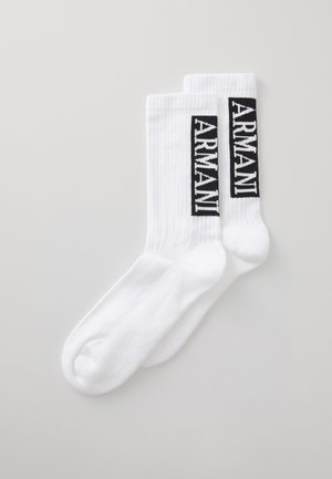 Chaussettes en coton blanches avec une texture côtelée, arborant un logo rectangulaire noir portant l'inscription "ARMANI" en blanc.