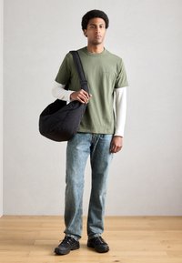 Musta olkalaukku, oliivinvihreä lyhythihainen t-paita valkoisen pitkähihainen paidan päällä, siniset farkut, mustat tennarit. Yksinkertainen, rento asu.