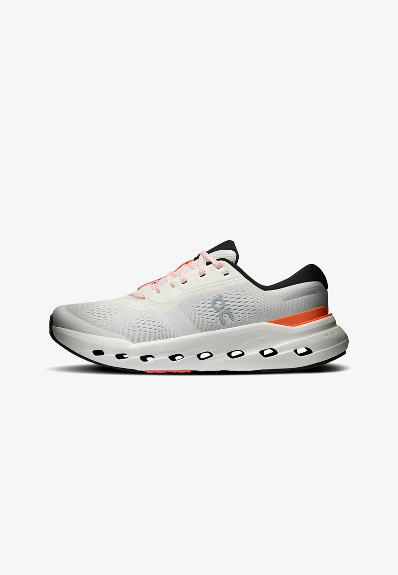 Chaussure de sport blanche avec semelle noire, bande orange sur la semelle intermédiaire, détail noir au talon, dessus en mesh et lacets blancs, vue de côté.