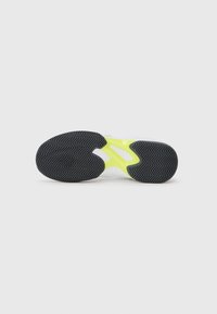 Talpa de pantof sport albă cu un model în pană, caracterizată printr-o talpă din cauciuc negru și un accent galben strălucitor în mijloc.