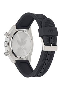 Montre à bracelet en caoutchouc noir avec un boîtier en acier inoxydable, dotée d'un cadran rond et de trois boutons. L'arrière affiche le logo Adidas et un texte.