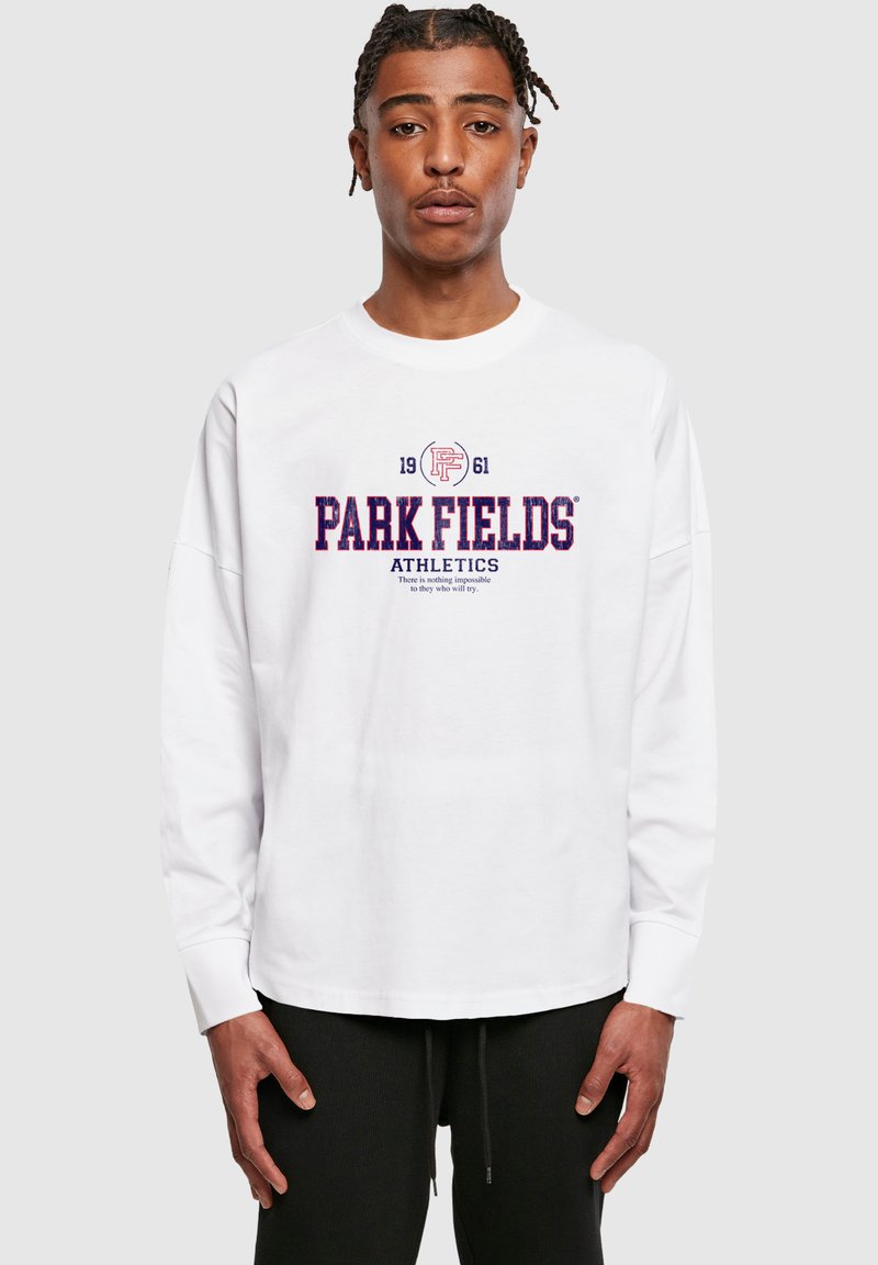 Fehér, hosszú ujjú póló, amelyen lila színű felirat található: "PARK FIELDS ATHLETICS", valamint egy logó és az alapítás éve: "1961". Egyszerű dizájn.