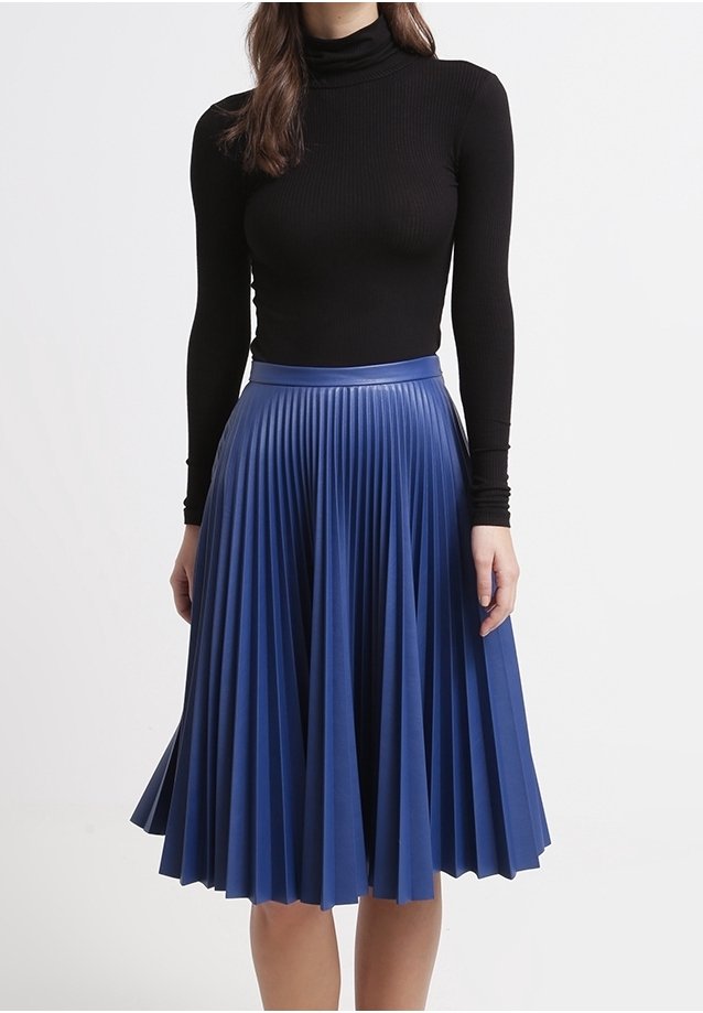 Plisserad blå kjol i slät tyg, med en åtsittande midja och en A-linjeform. Svart polotröja bärs ovanför kjolen.