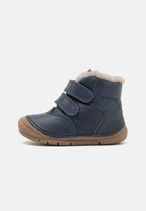 Bottine enfant en cuir bleu marine avec doublure en fourrure beige, deux bandes Velcro et semelle en caoutchouc marron texturée.