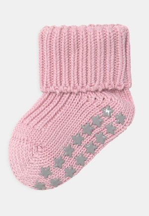 Różowa dziergana skarpetka z prążkowanym ściągaczem, posiadająca szare, gwiazdkowe, antypoślizgowe wstawki na podeszwie. Tekstura miękka, o przytulnym wyglądzie.