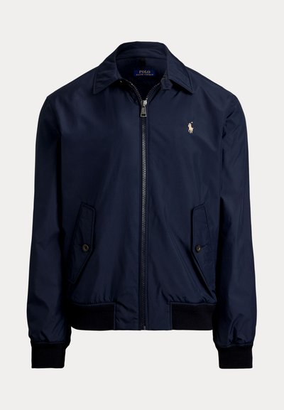 Ναυτικό μπλε bomber jacket από μαλακό ύφασμα, με φερμουάρ μπροστά, δύο πλάγιες τσέπες και ένα μικρό λογότυπο στο αριστερό στήθος.