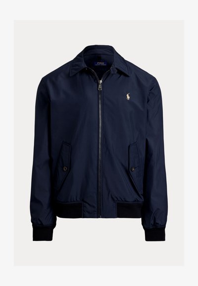 Ναυτικό μπλε bomber jacket από μαλακό ύφασμα, με φερμουάρ μπροστά, δύο πλάγιες τσέπες και ένα μικρό λογότυπο στο αριστερό στήθος.