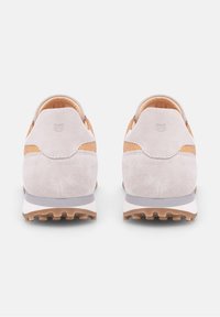Sneakers in suede grigio chiaro con un accento in pelle tan texture, forma arrotondata, collarino imbottito e suola in gomma con piccoli tacchetti per trazione.