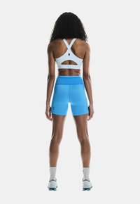 Reggiseno sportivo blu chiaro con design a taglio, abbinato a pantaloncini a vita alta coordinati. Entrambi i capi sono aderenti e realizzati in tessuto traspirante.