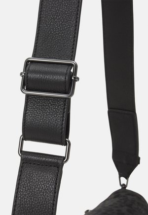 Sort tekstureret læder justerbar rem med metalspænde og beslag, fastgjort til en taskehjørne.