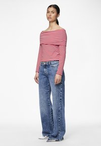 Rödrandig och vit långärmad topp med avskuren design, matchad med ljusblå vida slitna jeans.