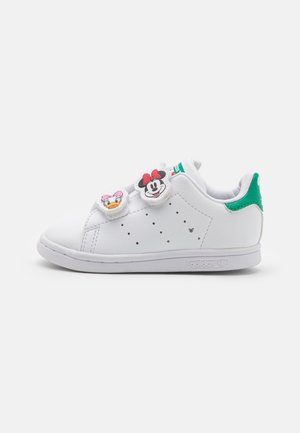 Baskets blanches Adidas avec languette verte au talon et deux bandes Velcro avec les visages de Minnie Mouse et Daisy Duck.