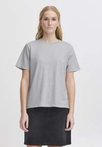 Pilkas trumpas rankovėmis marškinėliai, apvaliu kaklu, laisvas laisvasis kirpimas, minkšta tekstūra, derinami su juodais džinsiniais sijonais, minimalizmo dizainas, be raštų.