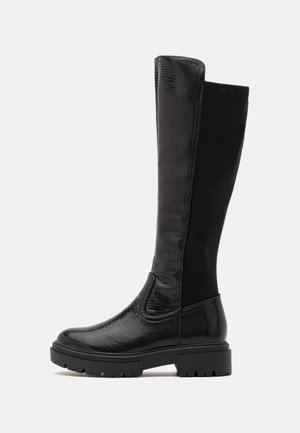 Bottes noires jusqu'aux genoux avec une tige en cuir texturé et un haut en tissu noir lisse. Caractéristiques d'une semelle épaisse et de panneaux latéraux élastiques.